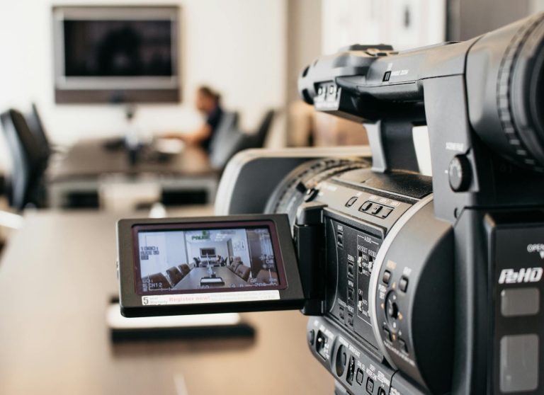 Close-up of professional video camera recording in modern office environment.